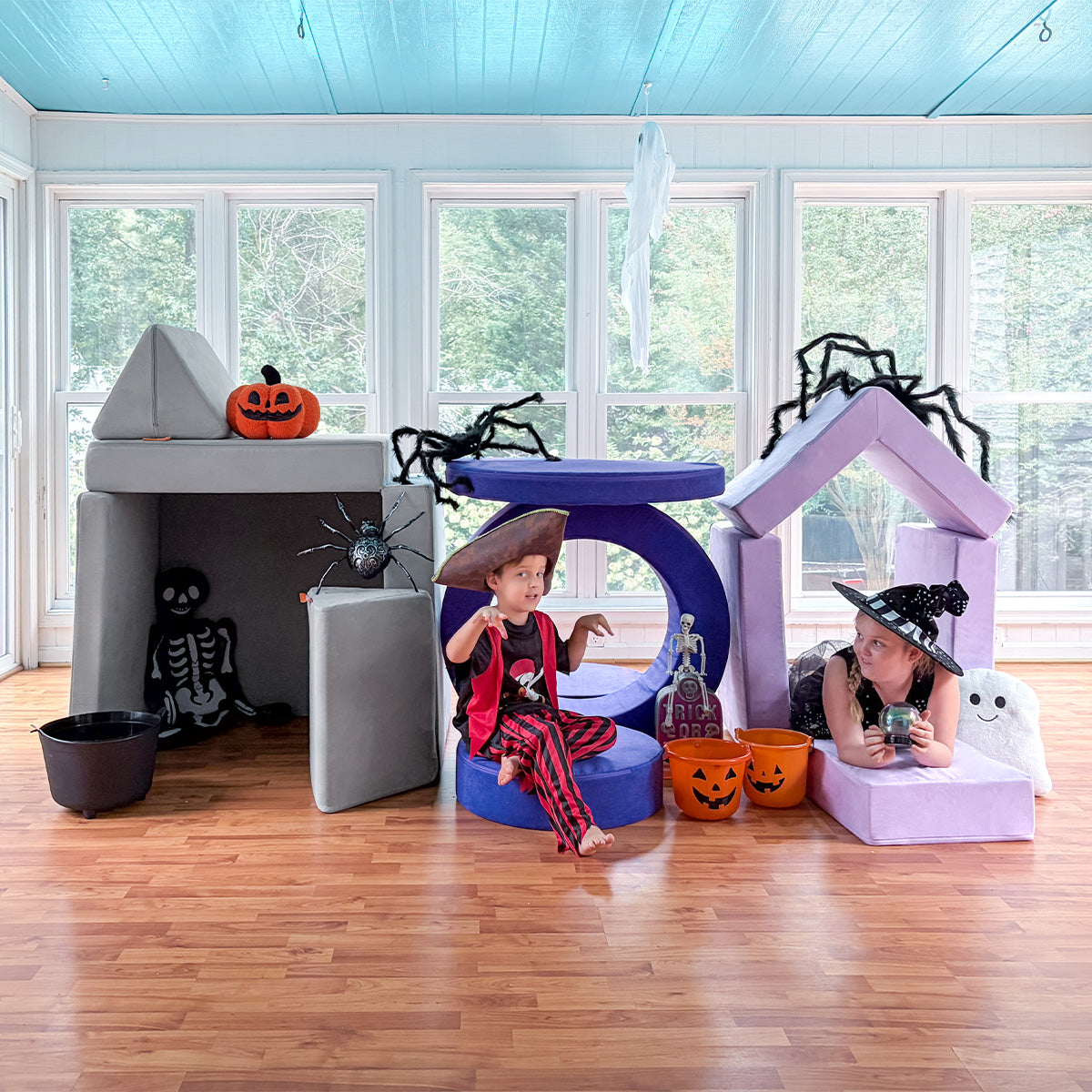 Two children in costume play amongst three forts made from a gray Nugget, indigo Chunk, and lilac Smore.