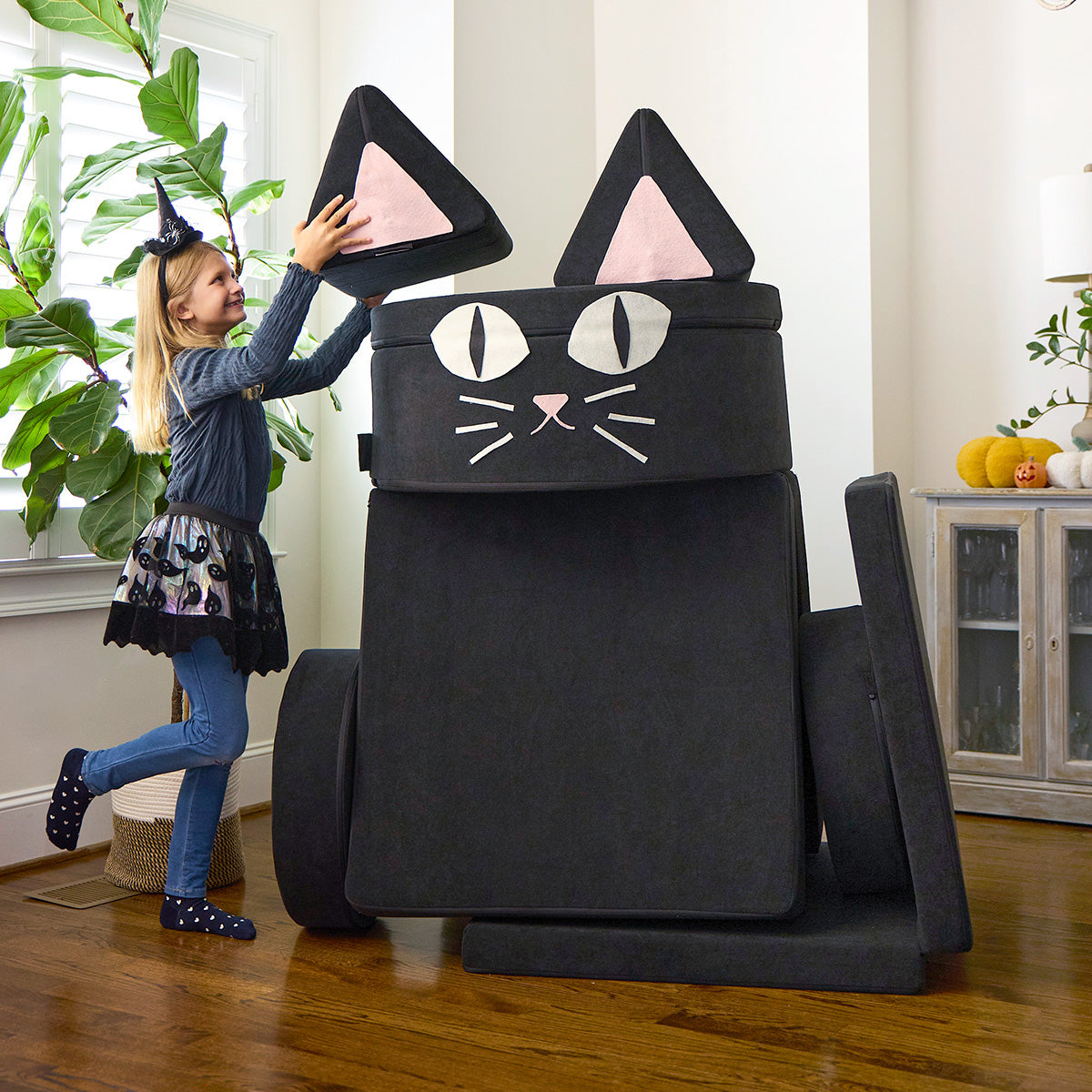 A child puts the finishing touches on a giant black cat, made from a black Chunk and Nugget, plus felt for the cat face.
