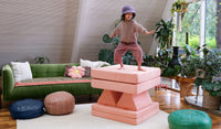 A young child pretends to surf on the stacked pieces of a Blossom light peach play couch by Nugget.