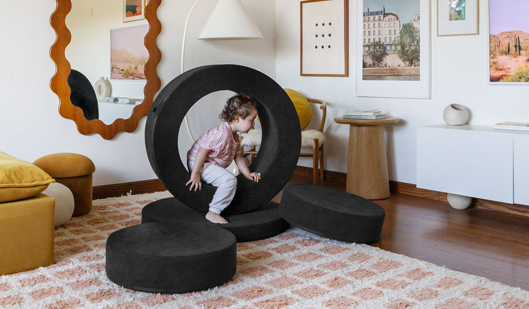 A child crawls through the hoop of a Catwalk all-black Chunk play ottoman.