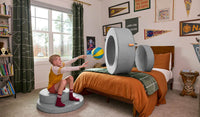 A child throws a ball through the hoop of a Koala light gray Chunk play ottoman.