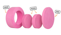 Four pieces of a candy pink Chunk play ottoman lined up: one large hoop, two sturdy nesting, and one wider pad for the lid.