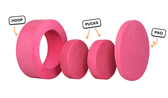 Four pieces of a hot pink Chunk play ottoman lined up: one large hoop, two sturdy nesting, and one wider pad for the lid.