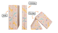 Four pieces of a unicorn-patterned Nugget play couch lined up: one foldable base, one foldable cushion, and two triangular pillows.