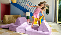 A child dances on a Moonshot lilac purple play couch by Nugget.