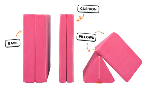 Four pieces of a hot pink Nugget play couch lined up: one foldable base, one foldable cushion, and two triangular pillows.