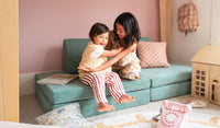 Two siblings hug and play on a Seamonster sea green play couch by Nugget, set up in a kids' sofa configuration.