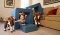 A child plays with toy horses in a makeshift barn made from the three pieces of a dark-wash denim play chair.