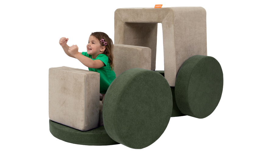 A child pretends to drive a vehicle while playing on a car build, made from a beige Smore and a forest green Chunk.