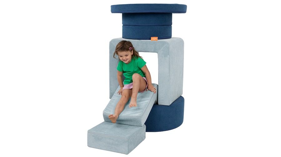 A child slides down the elbow of a light blue Smore, stacked into a small fort with a navy blue Chunk.