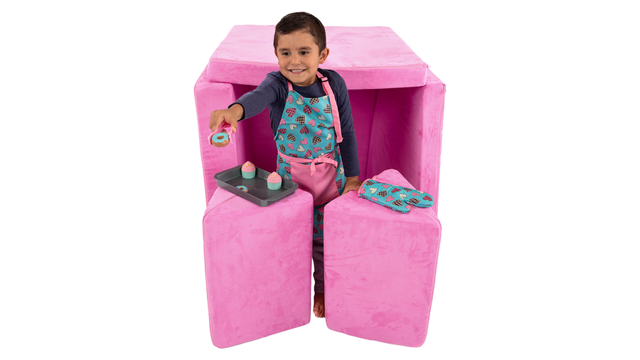 A child offers pretend baked goods from his small cafe Nugget build, created using one pink Nugget play couch.