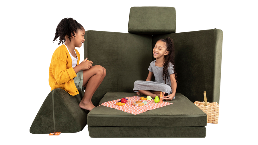 wo children share a Nuggety picnic lunch, across a picnic table build, created using one forest green Nugget play couch.