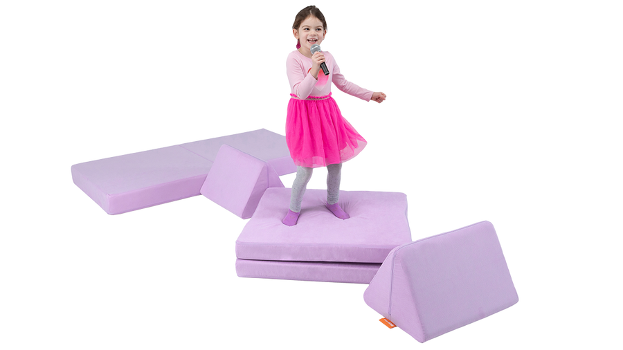 A child sings into a microphone and dances on a one-Nugget stage build, made from a light purple Nugget play couch. 