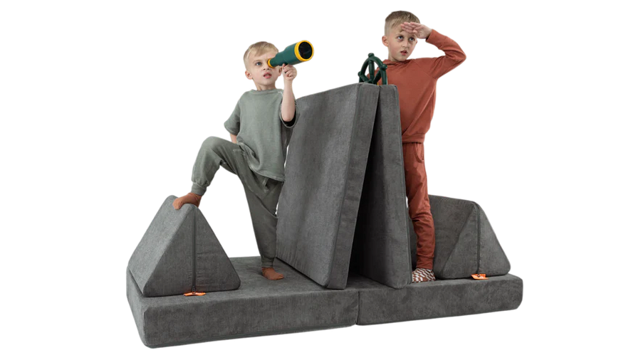 Two children eye the horizon from their one-Nugget boat build, made from a charcoal gray Nugget play couch.