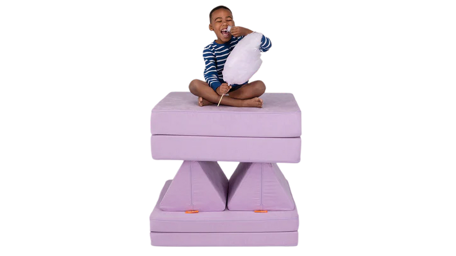 A child eats light purple cotton candy from his tower build — created using one light purple Nugget play couch.