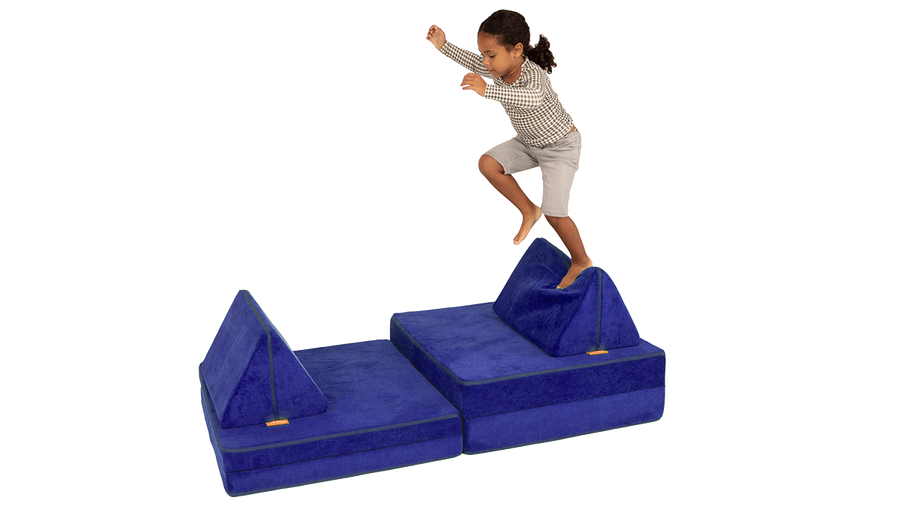 A child prepares to jump across the pieces of an indigo Nugget play couch.