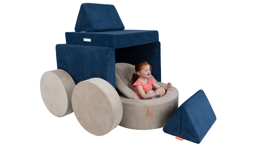 A child engages her imagination to pretend a Nugget play couch and Chunk play ottoman are a large semi-truck.