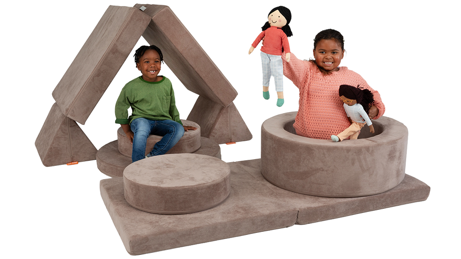 Two children smile and play on the pieces of a taupe Nugget play couch and Chunk play ottoman.