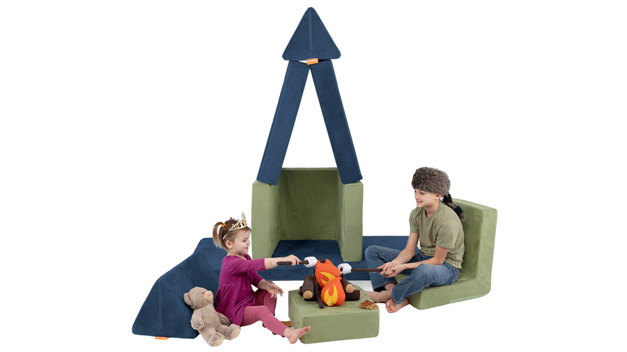 Two children sit by a pretend firepit at campsite made from a Nugget play couch and Smore play chair.
