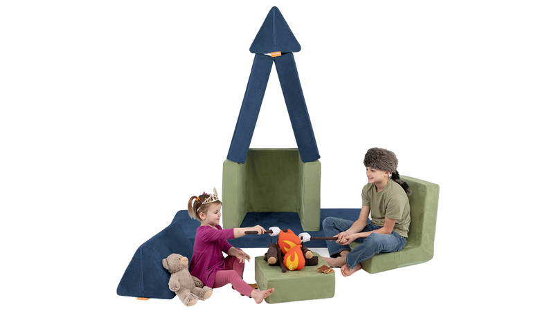Two children sit by a pretend firepit at campsite made from a Nugget play couch and Smore play chair.