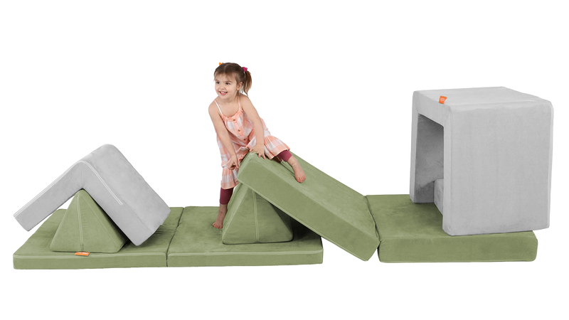 A child climbs on an obstacle course built from the pieces of a Nugget play couch and Smore play chair.