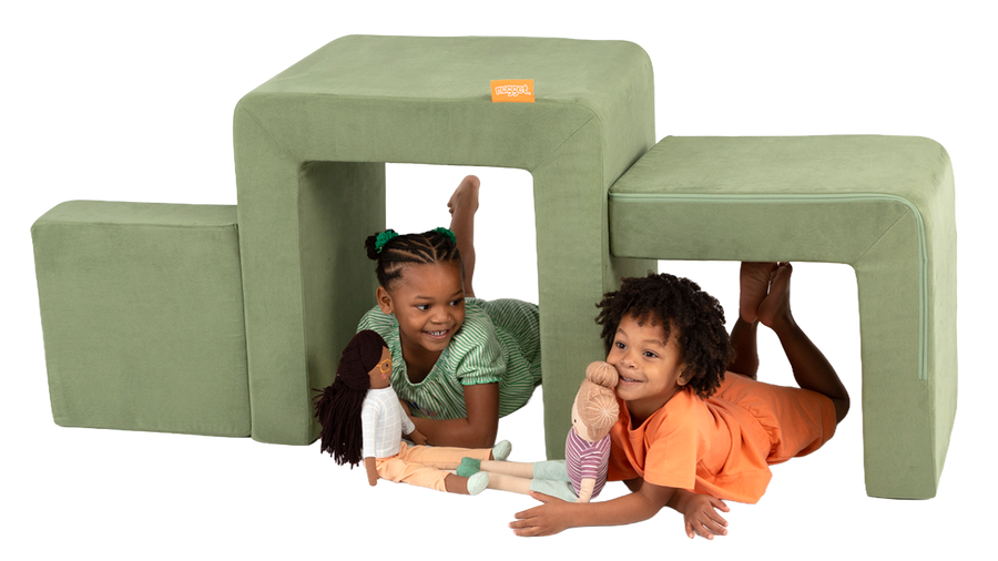 Two children play with dolls inside the pieces of a sage green Smore play chair by Nugget.