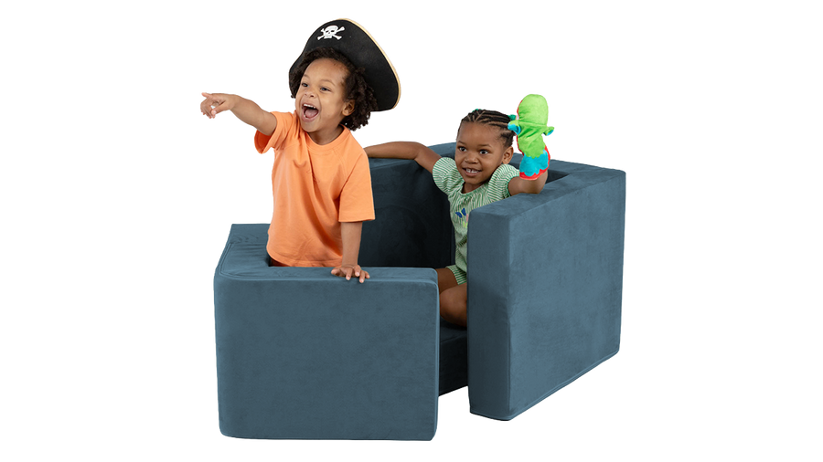 Two children pretend to sail in a pirate ship made from a navy blue Blueridge Smore play chair.