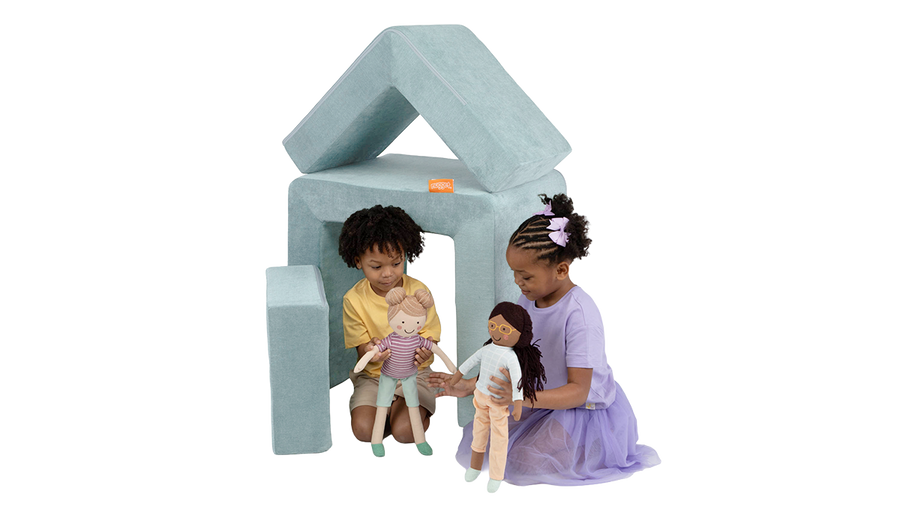 Two children play with dolls inside the pieces of a gray blue Smore play chair by Nugget, arranged to look like a house.