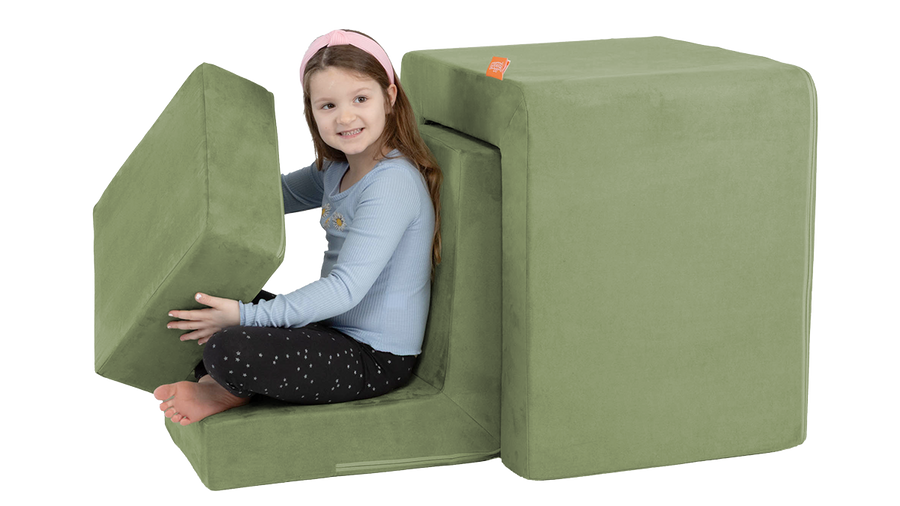 A child pretends to drive a car, built from the three pieces of a sage green Smore play chair.