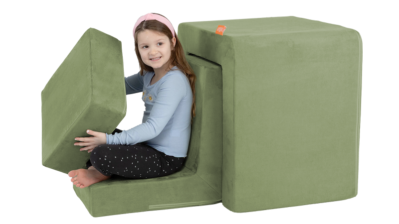 A child pretends to drive a car, built from the three pieces of a sage green Smore play chair.