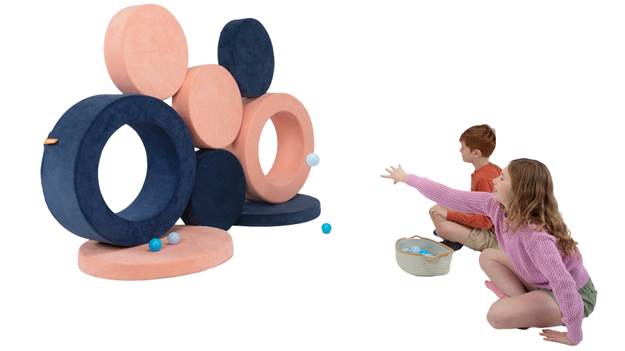 Two children toss small balls at a wall of targets made with the pieces of two Chunk play ottomans.