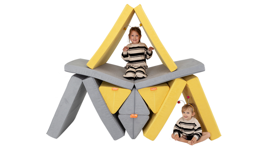 Two children dressed as bees play inside a beehive build, made with two Nugget play couches.