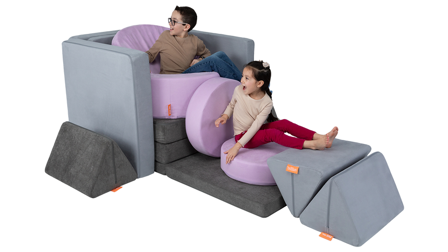 Two children play in a play furniture car build, made from two Nugget play couches and one Chunk play ottoman. 