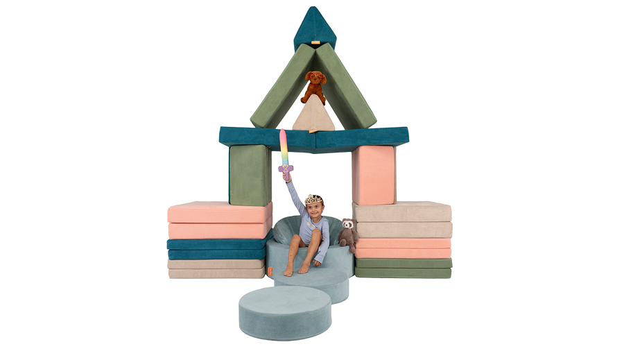A child sits triumphant on a Chunk play ottoman throne under a four-Nugget castle trellis.