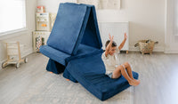 A child slides down the ramp of a Blueridge navy blue play couch by Nugget.