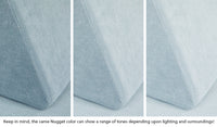 Close-up of a Nugget pillow in Surfside light gray-blue across three lighting situations. One color can present as a range of tones depending on the room.
