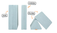 Four pieces of a light gray-blue Nugget play couch lined up: one foldable base, one foldable cushion, and two triangular pillows.